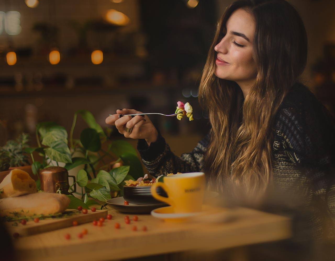 Mujer disfrutando de su comida en la mesa de un restaurante